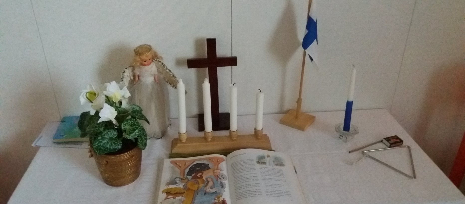 Kerhon alttaripöydällä adventtikynttilät, itsenäisyyspäivän kynttilä ja Suomenlippu,raamattu, risti ja kukkia
