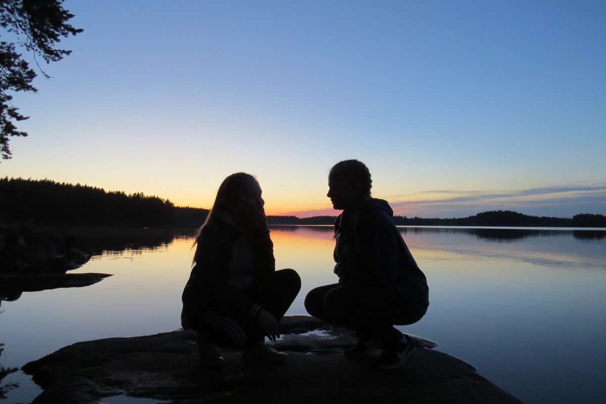 Nuoret järvenrannalla auringonlaskussa